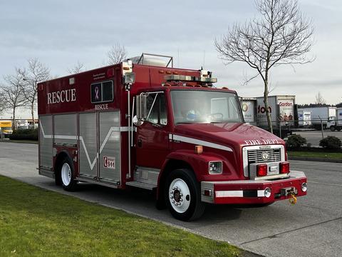 A red 1994 Freightliner FL80 rescue vehicle with a white stripe and various emergency lights and equipment on the exterior