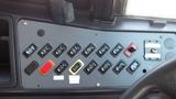 Close-up of a control panel featuring multiple switches and buttons labeled for various functions in a 2014 Freightliner Thomas Bus Diesel model