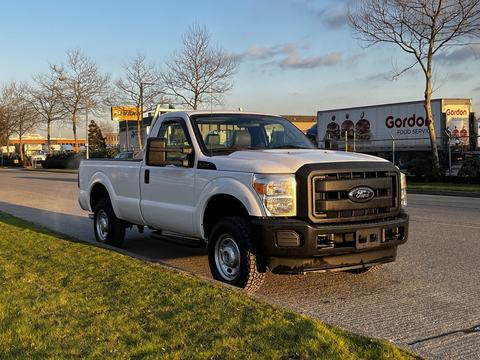 A 2012 Ford F-250 pickup truck in white with a black grille and no bed cover parked on a road