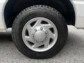 A silver wheel from a 2008 Ford Econoline featuring a five-spoke design and a rugged tire with deep treads