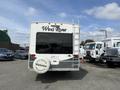 A white and grey 2013 Outdoor Wind River RV with a spare tire cover and a ladder on the back is parked in a lot