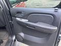 A 2011 Chevrolet Avalanche door panel featuring a handle and control buttons with a textured black finish and a circular speaker at the bottom