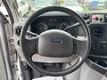 Steering wheel of a 2014 Ford E-350 with Ford logo visible and various controls on the dashboard