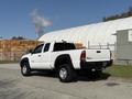 A white 2015 Toyota Tacoma pickup truck is parked with its bed facing the viewer showcasing its sleek design and wheels