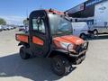 A 2018 Kubota ATV with an orange and black design featuring four wheels and a compact cab for two passengers