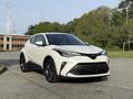 A white 2021 Toyota C-HR with a sleek design and black accents parked on a road