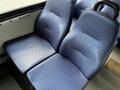 Two blue textured seats in a vehicle interior with a smooth floor and arm rests