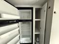 A black and white refrigerator with shelves and compartments visible inside alongside a small cabinet with a door on the right