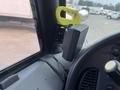 A close-up of a 2007 Freightliner B2 dashboard featuring a mounted speaker and a green handling tool attached to the side