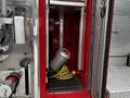 A compartment of a 1991 Sutphen Deluge fire truck displaying a coiled yellow hose and a silver fire nozzle inside