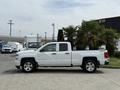 A white 2018 Chevrolet Silverado 1500 pickup truck is parked with its side visible showcasing its four-door design and shiny alloy wheels