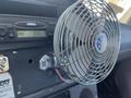 A metal desktop fan attached to the dashboard of a 2007 Freightliner M2 106 with a digital clock displaying the time 3:35