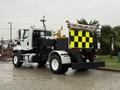 A 2016 Freightliner 108SD truck with a black and yellow checkerboard pattern on the rear and equipped with various tools and equipment on the back