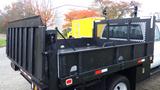 A black 2011 Ford F-550 truck with a flatbed and metal railing at the back designed for utility and hauling work