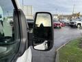 A 2023 Ford Transit van with a close-up view of its side mirror reflecting the sky and surrounding vehicles