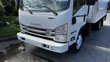 A white 2016 Isuzu NPR truck with large headlights and a prominent grille facing forward