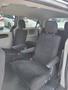 Interior view of a 2012 Dodge Grand Caravan with two black fabric captain's chairs facing each other and armrests on each side