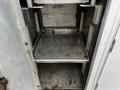 A 2016 Ford F-550 with an empty metal storage compartment featuring removable shelves and a gray metallic finish
