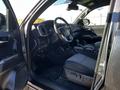 Interior view of a 2021 Toyota Tacoma showing the driver seat dashboard and controls with a black fabric seat and floor mats