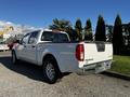 A 2015 Nissan Frontier pickup truck is parked with its rear view visible showcasing its clean white exterior and silver wheels