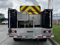 A 2007 Ford F-550 with a specialized rear compartment featuring bright yellow and red reflective markings and storage boxes on either side