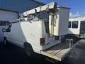 A white 2008 Ford Econoline van with a bucket lift attached to the roof and a platform at the rear