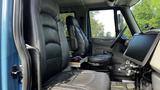 Interior of a 2009 International 4300 featuring two leather seats one of which is equipped with a reclining feature and a dashboard with various controls and a monitor