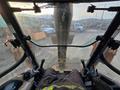 View from the operator's seat of a 2015 Case 590SN backhoe loader featuring dual joysticks and a clear front windshield