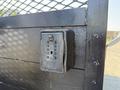 A black lockbox mounted on a gate with a grid pattern and numbered dials for a combination lock