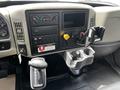 Cab interior of a 2019 International 4300 featuring a dashboard with dials switches and a gear shift along with a console holding cup holders and a control panel