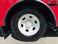 A close-up of a white wheel with five circular holes mounted on a black tire labeled Michelin on a red truck