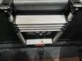 A folded aluminum ladder secured against a surface with gray and black components featuring a small object atop it