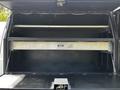 Interior storage compartment of a 2016 Ford F-550 with a metallic shelf and a locking mechanism