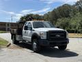 A 2012 Ford F-450 SD truck with a flatbed and visibility lights on the roof parked in a lot