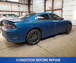 A blue 2022 Dodge Charger with a sleek design and dark wheels is parked in a garage setting showing signs of dirt on its exterior