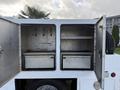 A 2008 Ford F-450 with two open metal compartments revealing empty shelves and bins inside