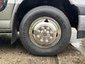 A close-up of a silver wheel and tire from a 2020 Chevrolet Express featuring a shiny hubcap and a rugged tread design on the tire