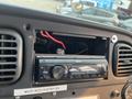 Dashboard of a 2007 Freightliner B2 featuring a car radio unit with wiring visible in the open compartment and control buttons for audio settings