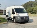 A 2017 RAM Promaster van with a white body and a dark gray front, parked with a slight angle, showcasing its utilitarian design and large cargo space