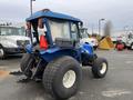 A blue 2007 New Holland TN70A tractor with large rear tires and a protective canopy is positioned at an angle showing its back and side