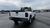 A white 2013 Chevrolet Silverado 1500 pickup truck with a black bed liner and silver wheels parked in a lot with its tailgate down