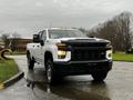 A 2021 Chevrolet Silverado 3500HD truck with a white exterior and a black front grille parked on a wet road