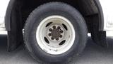 A close-up of a white wheel with a black tire from a 2011 Ford Econoline featuring eight visible lug nuts and a slightly worn tread