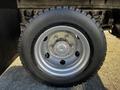 Close-up of a silver alloy wheel on a tire of a 2014 Mitsubishi Fuso FE showing five lug nuts and a smooth surface