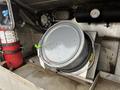 A metal drum with a slightly rusted surface is secured in a compartment of a 2018 Ford F-550 vehicle