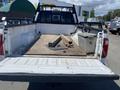 A 2016 Ford F-350 SD truck with an open bed containing wooden planks and metal tools including a metal box and various attachments