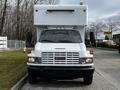 A white 2006 GMC C5000 front view with a distinctive grill and headlights, accompanied by a large box-like cargo area mounted behind the cabin