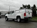 A white 2019 Chevrolet Colorado pickup truck with a camper shell on the bed parked at an angle showing the rear and side view