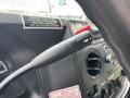 A close-up view of the control lever of a 2014 Ford E-350 with a warning label and various dashboard controls in the foreground