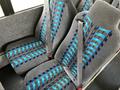 Two gray bus seats with blue and black striped patterns and attached seat belts